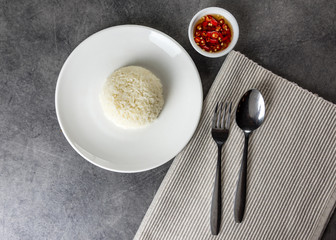 Jasmine rice serve on a plate with spoon and fork in restaurant, plate of steamed white rice