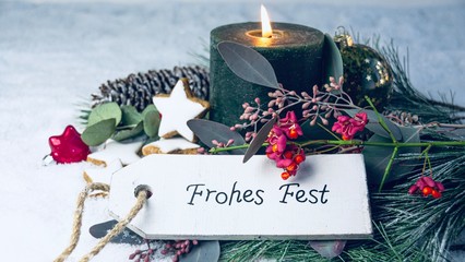 Brennende grüne Adventskerze mit Weihnachtsgüßen -  Frohes Fest - Weihnachtsdekoration