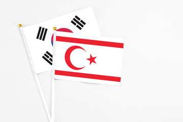 Northern Cyprus and South Korea stick flags on white background. High quality fabric, miniature national flag. Peaceful global concept.White floor for copy space.