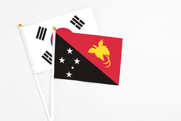 Papua New Guinea and South Korea stick flags on white background. High quality fabric, miniature national flag. Peaceful global concept.White floor for copy space.