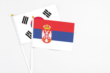 Serbia and South Korea stick flags on white background. High quality fabric, miniature national flag. Peaceful global concept.White floor for copy space.