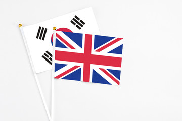 United Kingdom and South Korea stick flags on white background. High quality fabric, miniature national flag. Peaceful global concept.White floor for copy space.