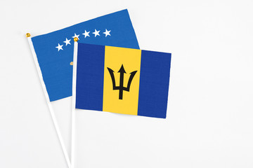 Barbados and Kosovo stick flags on white background. High quality fabric, miniature national flag. Peaceful global concept.White floor for copy space.