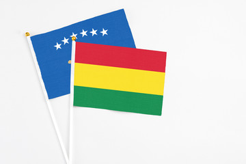Bolivia and Kosovo stick flags on white background. High quality fabric, miniature national flag. Peaceful global concept.White floor for copy space.