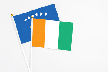 Cote D'Ivoire and Kosovo stick flags on white background. High quality fabric, miniature national flag. Peaceful global concept.White floor for copy space.