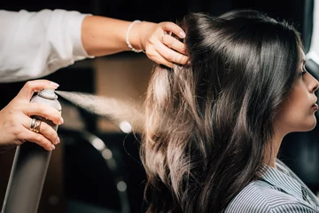  Haarstylist die het haar van vrouwen spuit © Microgen