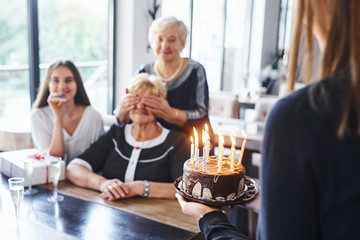 Senior woman with family and friends celebrating a birthday indoors