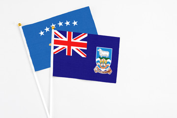 Fototapeta premium Falkland Islands and Kosovo stick flags on white background. High quality fabric, miniature national flag. Peaceful global concept.White floor for copy space.