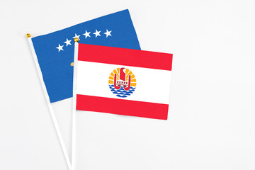 French Polynesia and Kosovo stick flags on white background. High quality fabric, miniature national flag. Peaceful global concept.White floor for copy space.