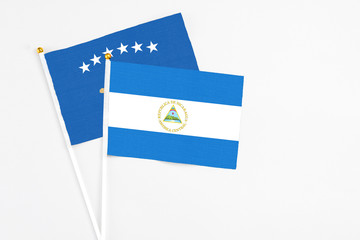 Nicaragua and Kosovo stick flags on white background. High quality fabric, miniature national flag. Peaceful global concept.White floor for copy space.