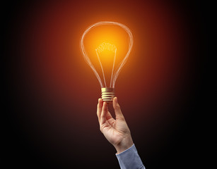 Hand holding light bulb on dark background. New idea concept