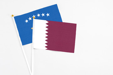 Qatar and Kosovo stick flags on white background. High quality fabric, miniature national flag. Peaceful global concept.White floor for copy space.