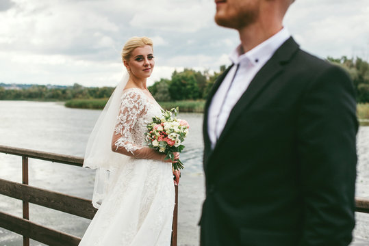 A young couple of newlyweds on the wooden pier by the water. Wedding photo shoot near river