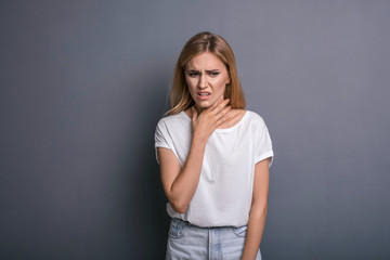 Caucasian woman in neutral casual outfit standing on a neutral grey background. Portrait with emotions: angry, pain, sickness and despair