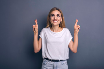 Caucasian woman in neutral casual outfit standing on a neutral grey background. Portrait with emotions: happiness, amazement, joy and satisfaction