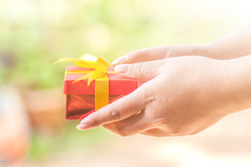 Woman holding a beautiful Red gift box in a gesture of Give to. concept of ​​giving gifts on a happy or successful day. Soft selective focus.