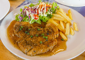 pork meat grilled with fresh vegetable salad and potatoes on a white plate in restaurant,select focus.