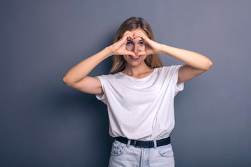 Caucasian woman in neutral casual outfit standing on a neutral grey background. Portrait with emotions: happiness, amazement, joy and satisfaction