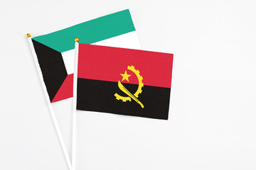 Angola and Kuwait stick flags on white background. High quality fabric, miniature national flag. Peaceful global concept.White floor for copy space.