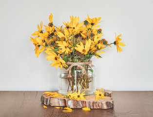  Bouquet of jerusalem artichokes in a glass vase. Rustic interior decoration.