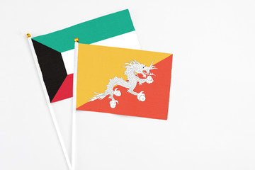 Bhutan and Kuwait stick flags on white background. High quality fabric, miniature national flag. Peaceful global concept.White floor for copy space.