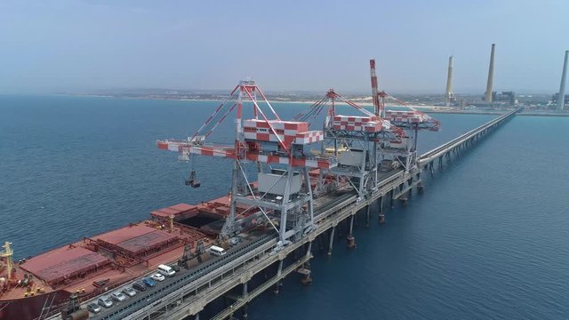 Aerial footage of a Large Bulk carrier offloading coal for a large scale power plant