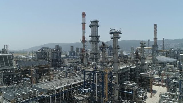Aerial footage of a large scale Oil refinery with smoke stacks and petroleum storage tanks
