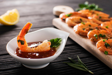 tails of shrimps with fresh lemon and rosemary in plate on wooden old background