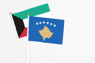 Kosovo and Kuwait stick flags on white background. High quality fabric, miniature national flag. Peaceful global concept.White floor for copy space.