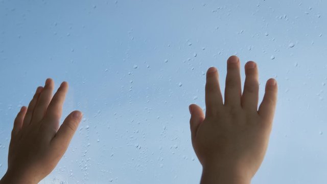 Hands of a child at the window.