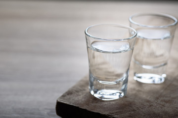 Vodka in a shot glass on a brown wooden background prepared for a party