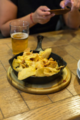 Chips in the pan and beer. In the background, a woman with a smartphone.