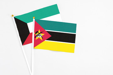 Mozambique and Kuwait stick flags on white background. High quality fabric, miniature national flag. Peaceful global concept.White floor for copy space.