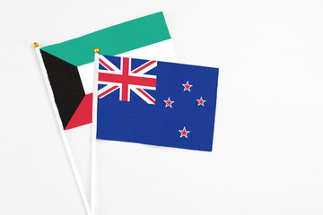 Fototapeta premium New Zealand and Kuwait stick flags on white background. High quality fabric, miniature national flag. Peaceful global concept.White floor for copy space.