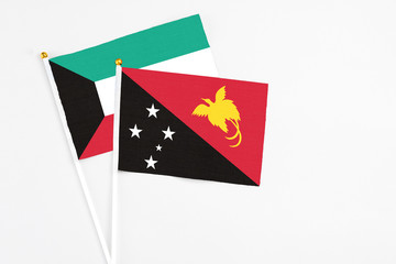 Papua New Guinea and Kuwait stick flags on white background. High quality fabric, miniature national flag. Peaceful global concept.White floor for copy space.