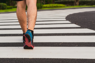 Naklejka na ściany i meble Closeup shoe. Male legs walking on the zebra crossing track. Safety road crossing concept