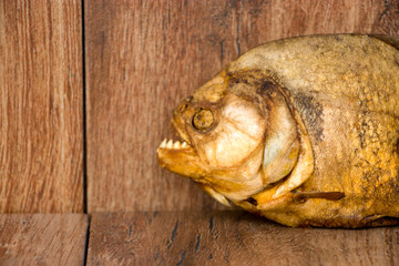 Smoked piranha on an old wooden background. Predatory river fish. River cannibal.