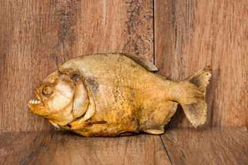 Smoked piranha on an old wooden background. Predatory river fish. River cannibal.