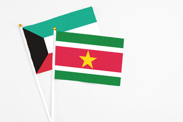 Suriname and Kuwait stick flags on white background. High quality fabric, miniature national flag. Peaceful global concept.White floor for copy space.
