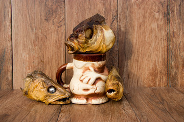 Smoked fish on an old wooden background with a clay glass. Bream, Pikeperch, Piranha. River fish.