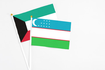 Uzbekistan and Kuwait stick flags on white background. High quality fabric, miniature national flag. Peaceful global concept.White floor for copy space.