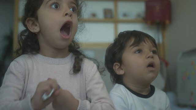 Two children react and get excited about something they see on TV
