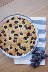 Italian sweet cake called focaccia with black grape on a wooden table