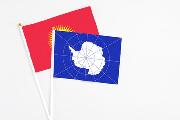 Antarctica and Kyrgyzstan stick flags on white background. High quality fabric, miniature national flag. Peaceful global concept.White floor for copy space.