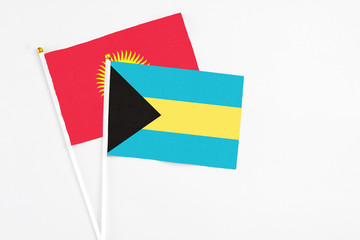 Bahamas and Kyrgyzstan stick flags on white background. High quality fabric, miniature national flag. Peaceful global concept.White floor for copy space.