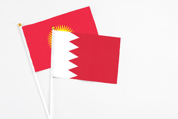 Bahrain and Kyrgyzstan stick flags on white background. High quality fabric, miniature national flag. Peaceful global concept.White floor for copy space.