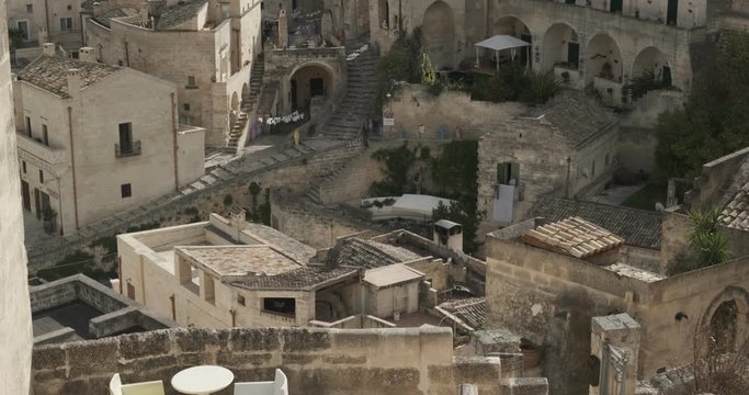 Roofs of houses in the Sassi of Matera transformed into hotels. Panoramic terrace with sofa and chair in white plastic.