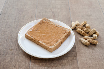 a classic slice of whole wheat bread with smooth peanut butter on wooden background