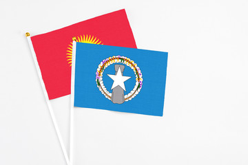 Northern Mariana Islands and Kyrgyzstan stick flags on white background. High quality fabric, miniature national flag. Peaceful global concept.White floor for copy space.