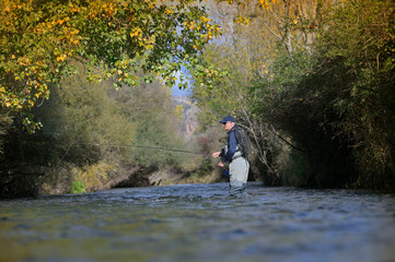 Fototapeta na wymiar fly fisherman in autumn and fast river